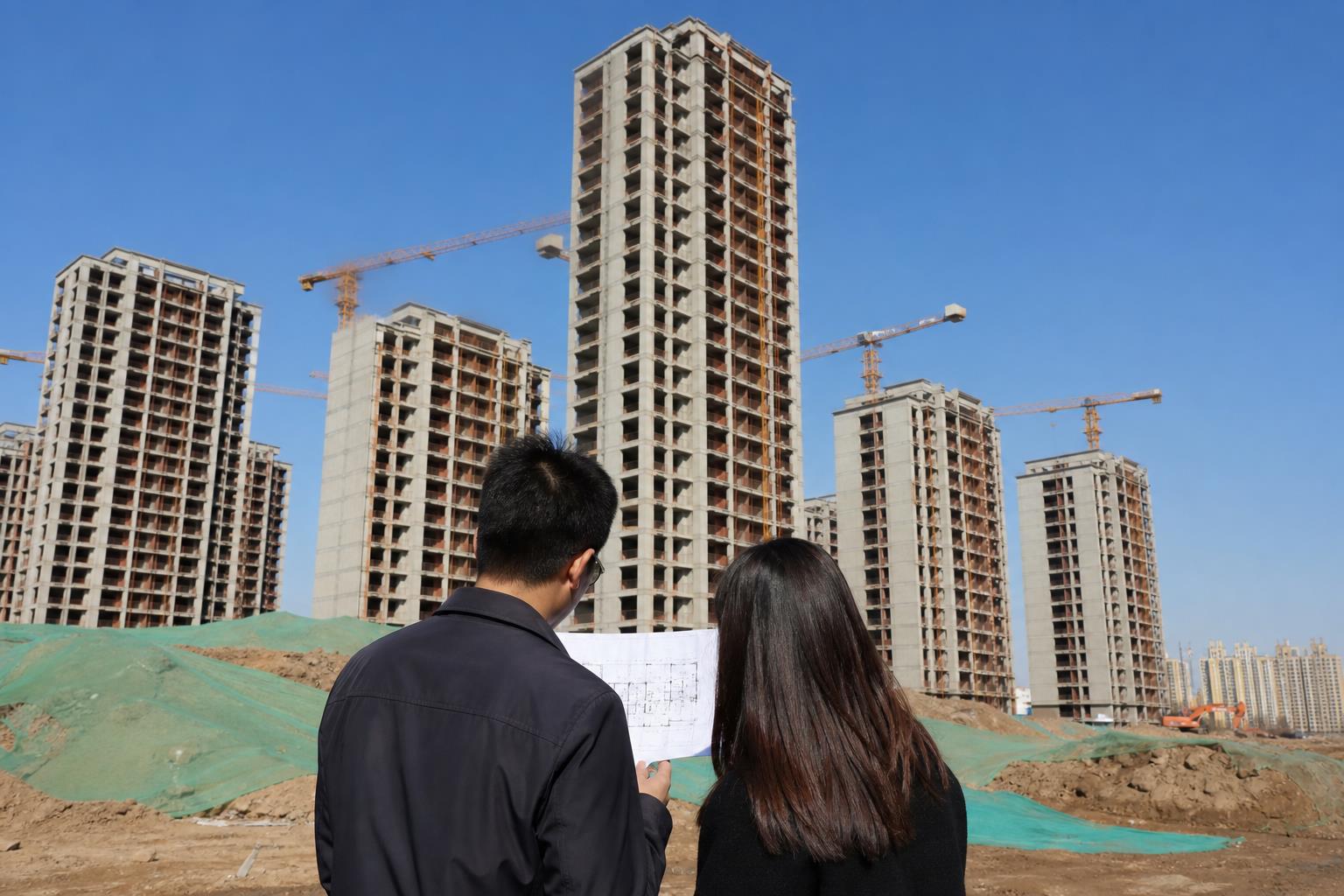 购房者在西安未央区在建住宅外核对楼栋和付款资料